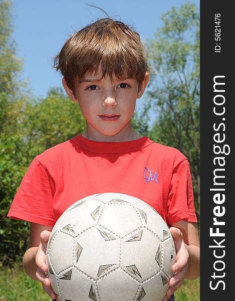 The boy in a red T-short holds before itself a football. The boy in a red T-short holds before itself a football