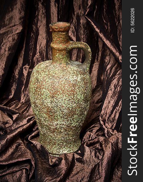 Ancient wine jug on brown hangings
