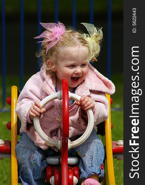 Happy young girl playing on spring rocker in park. Happy young girl playing on spring rocker in park.