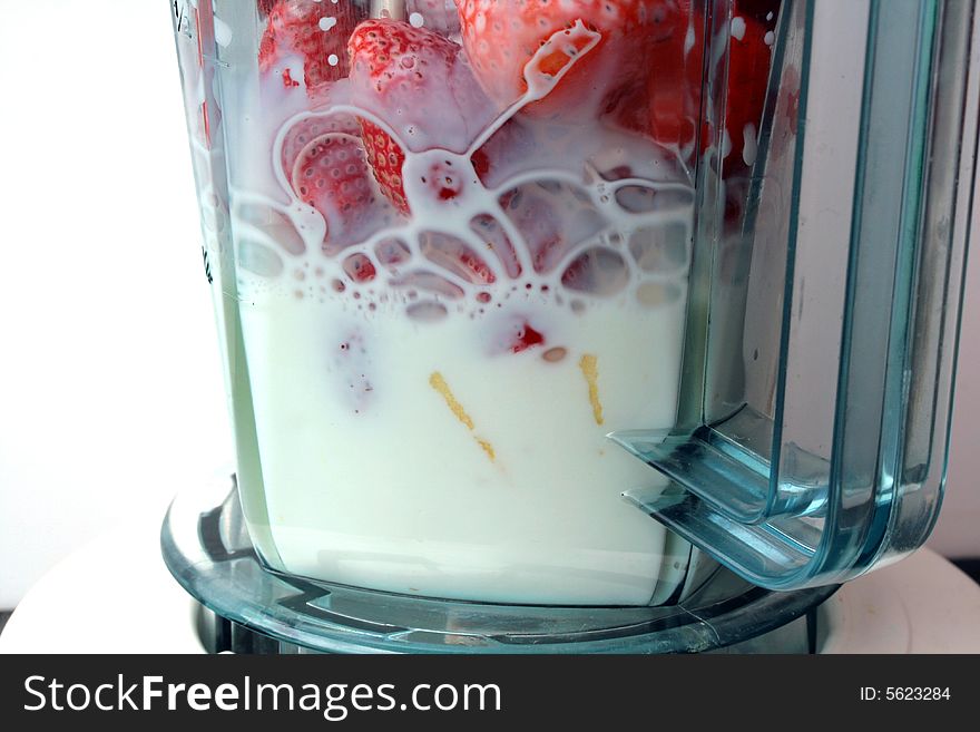 Strawberries and apple in blender  with milk.