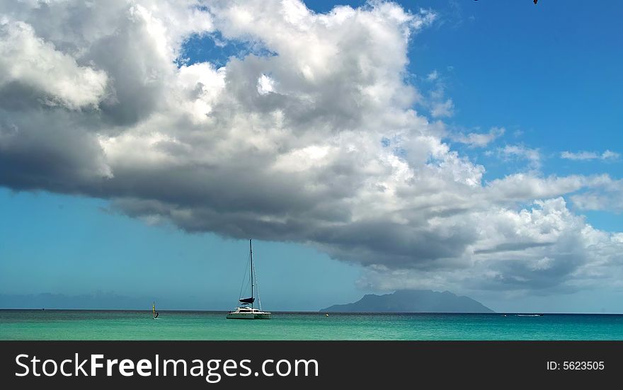 Catamaran boat is arriving to the tropical island . 
The sea , sky and clouds as background. Catamaran boat is arriving to the tropical island . 
The sea , sky and clouds as background.