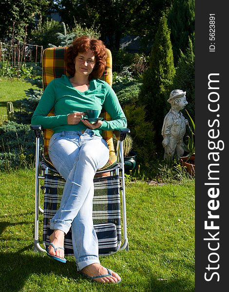 Woman with cap of tea sitting in garden