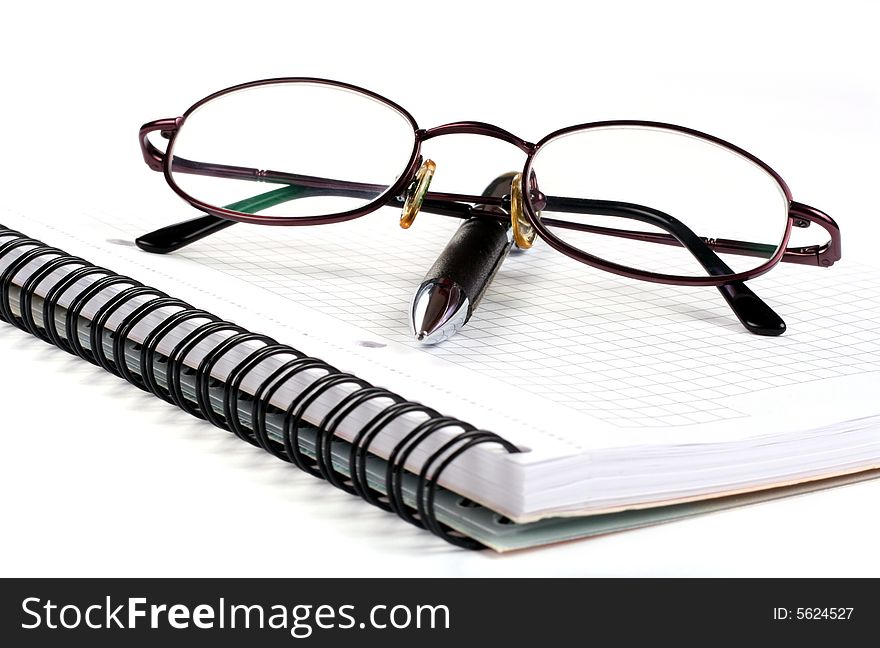 Notepad with eyeglasses and pen isolated on white background