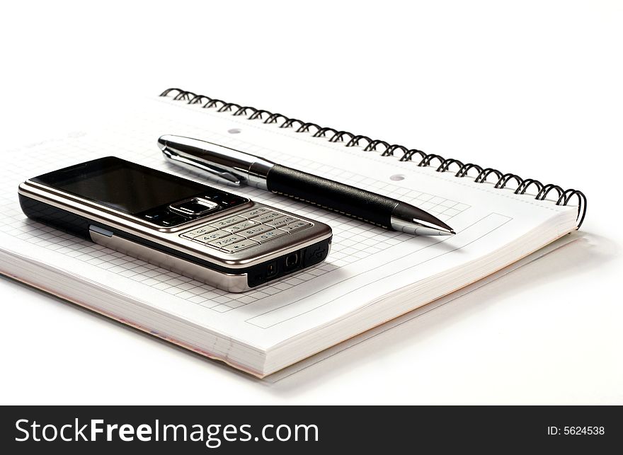Mobile phone pen and spiral notepad on white background