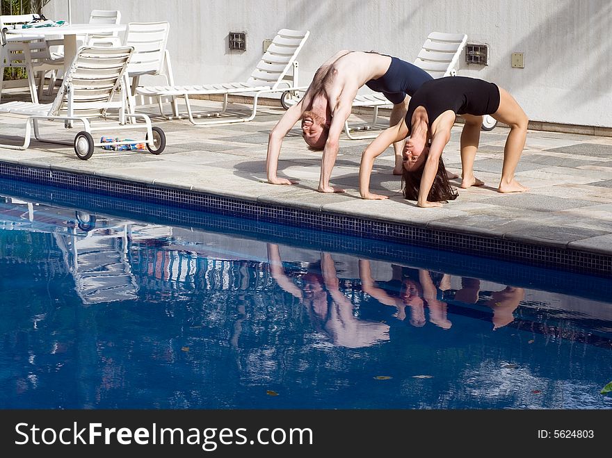 A couple near the pool, in a bridge position - horizontally framed. A couple near the pool, in a bridge position - horizontally framed