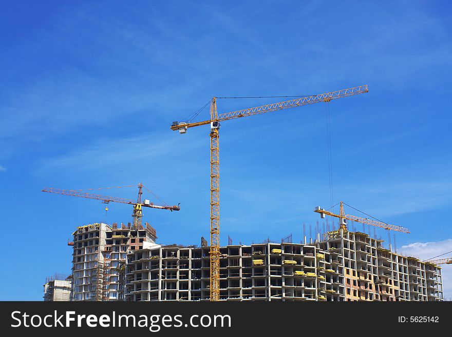 Cranes on sandy I protect under the blue sky. Construction of a complex of buildings