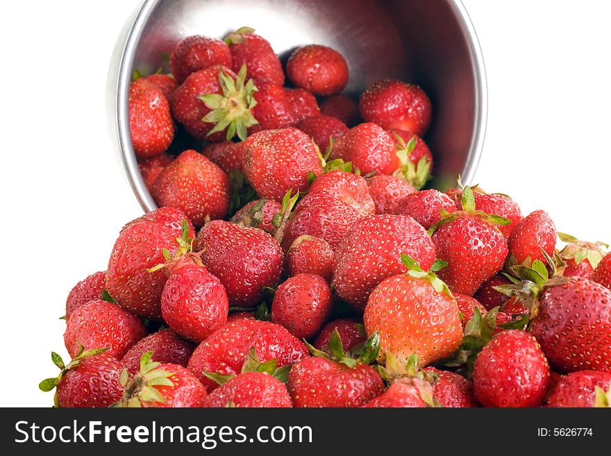 Fresh picked strawberries spill from a small stainless steel bowl. Fresh picked strawberries spill from a small stainless steel bowl