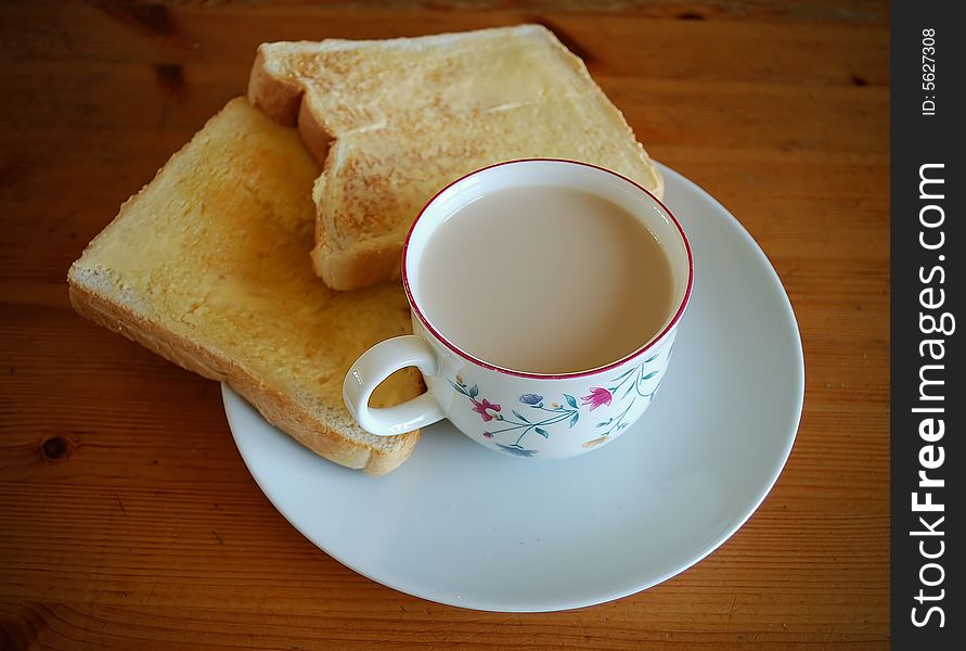 A cup of milk, bread and butter in a wooden table. A cup of milk, bread and butter in a wooden table