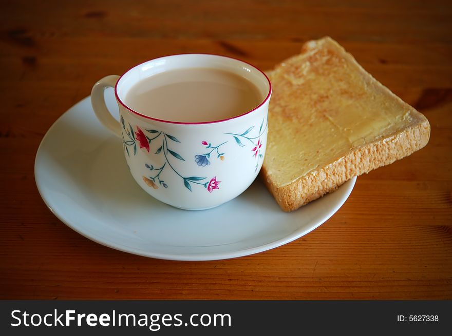 A cup of milk, bread and butter in a wooden table. A cup of milk, bread and butter in a wooden table