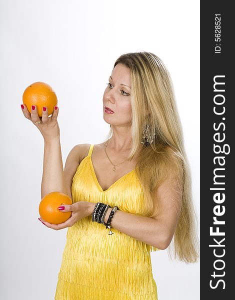 Blonde woman in yellow dress with orange in her hand. Blonde woman in yellow dress with orange in her hand