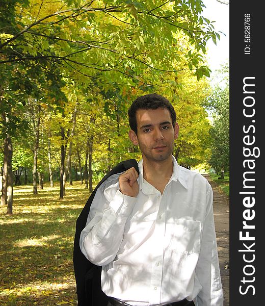 The young man is walking through the park. The young man is walking through the park