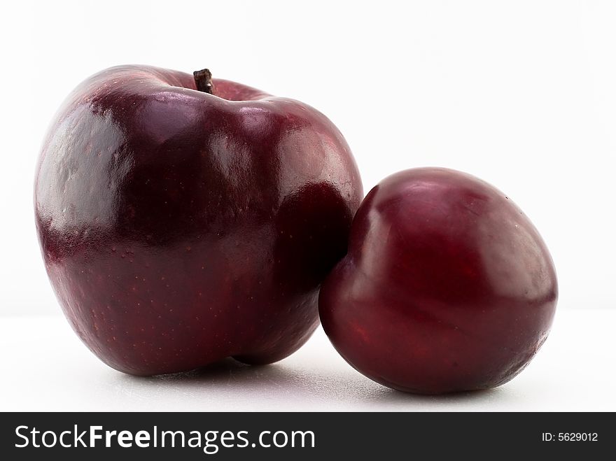 A red apple and ripe plum isolated on white. A red apple and ripe plum isolated on white.
