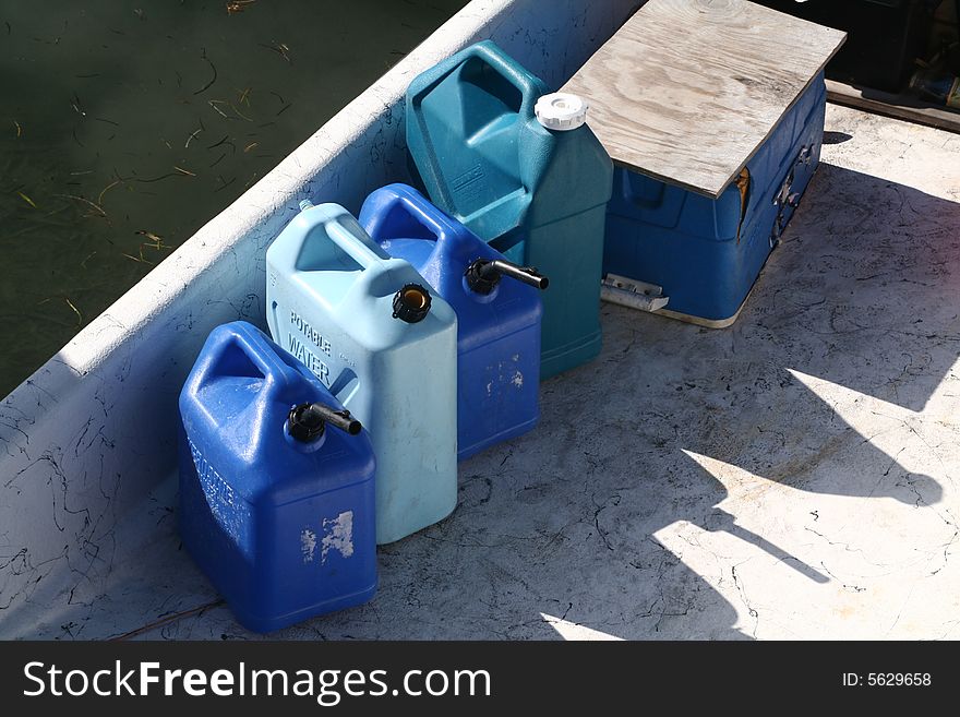 A sign of the times, several gas cans on the deck of a boat.
