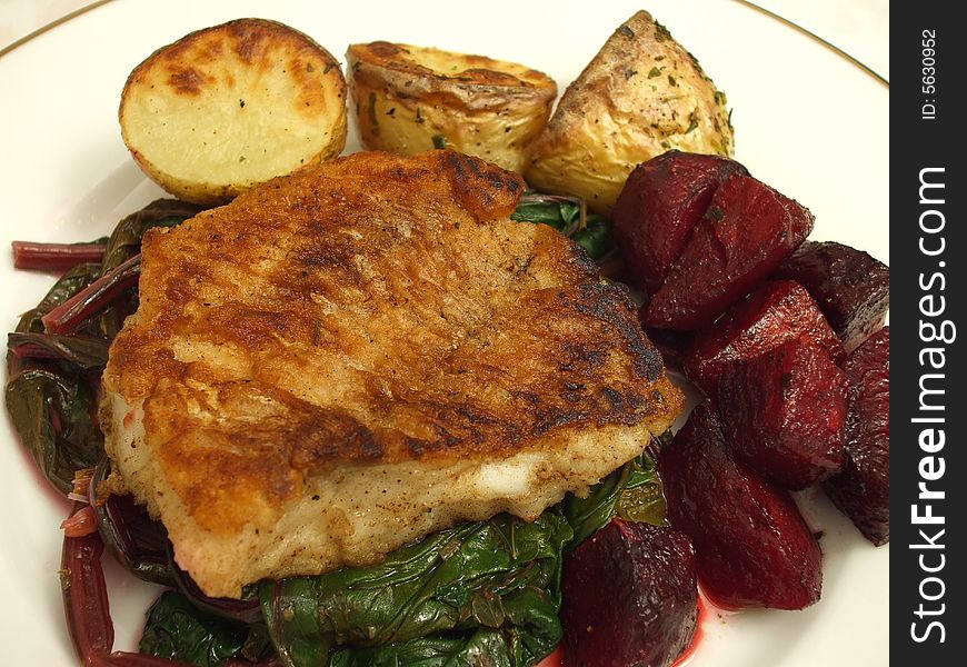 Photo of fillet of pan seared Tautog or Black Fish served with roasted beets, roasted potatoes and served on a bed of beet greens.  The Tautog or Black Fish can be substituted for any white meat fish and is quite good.