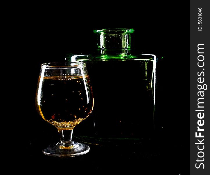An image of  bottles and glass on black background. An image of  bottles and glass on black background