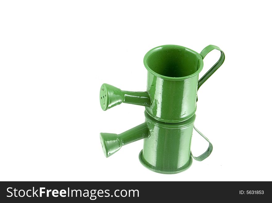 Green watering can doubled by reflecting in a mirror