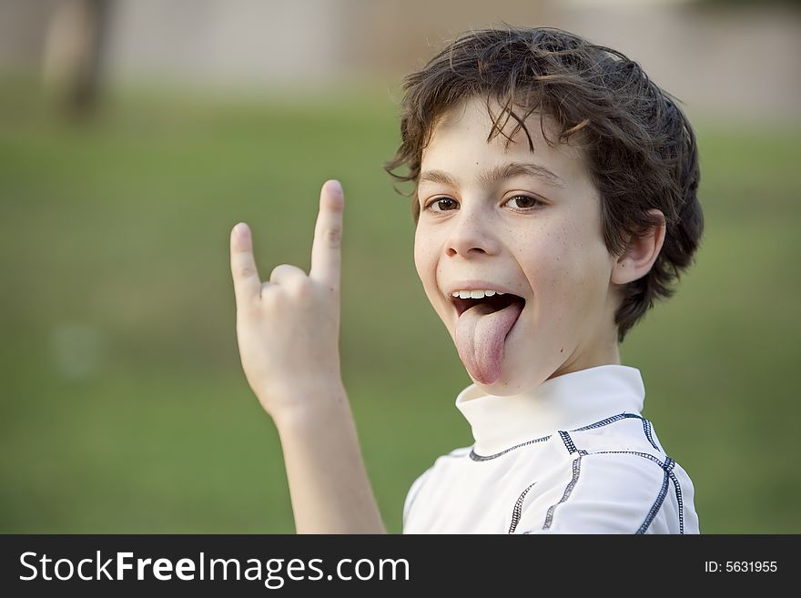 Boy sticking out his tongue and making a bull horn gesture with his hand. Boy sticking out his tongue and making a bull horn gesture with his hand