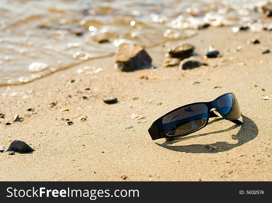 Sun protect glasses laying on sea coast