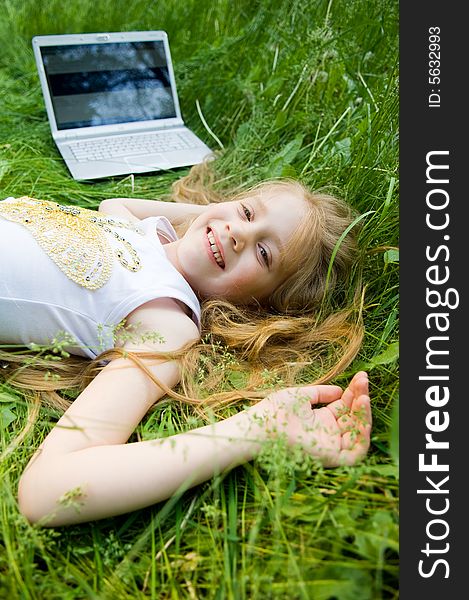 Smiling little girl with laptop in green grass. Smiling little girl with laptop in green grass