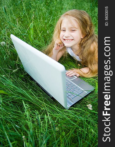 Cute little girl with laptop in green grass