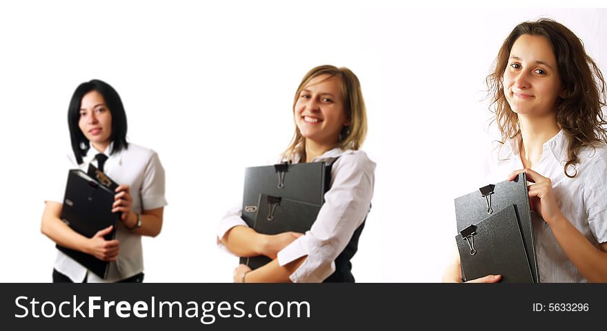 Three attractive businesswomen are smiling and they are holding folders. They are wearing elegant white shirts. Three attractive businesswomen are smiling and they are holding folders. They are wearing elegant white shirts.