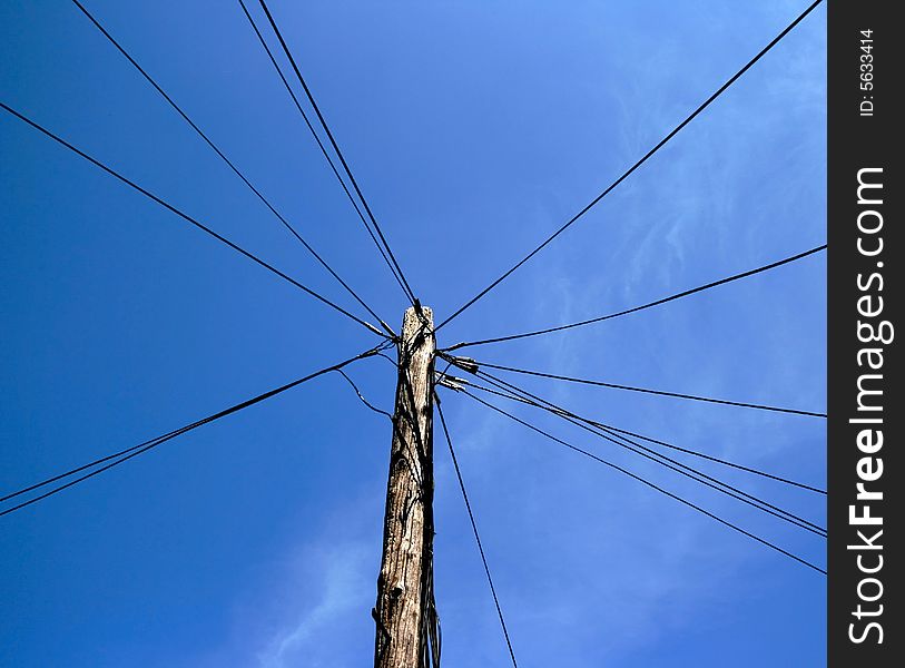 Wires stretch out from a telephone pole in an interesting pattern. Wires stretch out from a telephone pole in an interesting pattern.