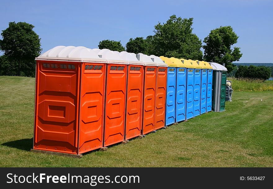 Several colorful outdoor toilets lined up ready for an outdoor event. Several colorful outdoor toilets lined up ready for an outdoor event.