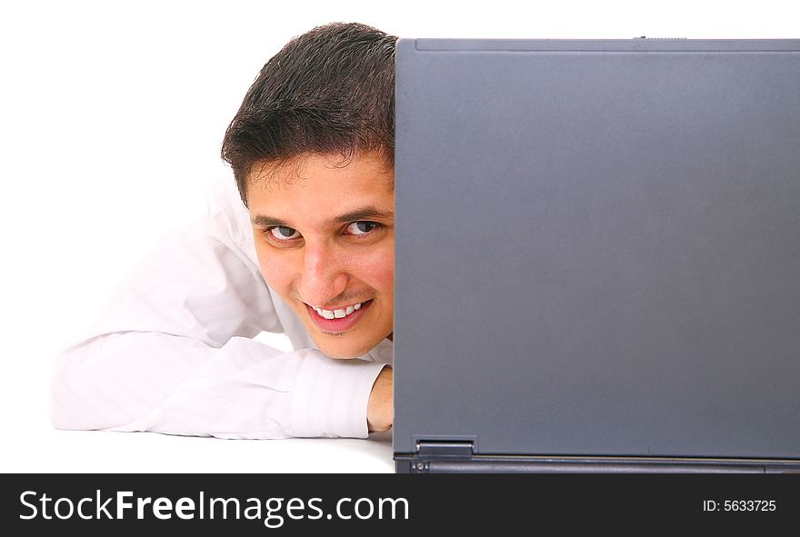 Smiling young man partially hides behind laptop. isolated on white background. Smiling young man partially hides behind laptop. isolated on white background