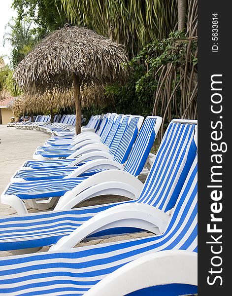 Blue and white striped lounge chairs around a luxury resort swimming pool. Blue and white striped lounge chairs around a luxury resort swimming pool