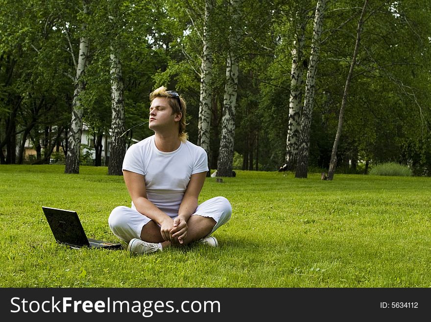 Casual man works on laptop on the grass