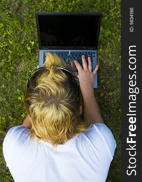 Casual man works on laptop on the grass