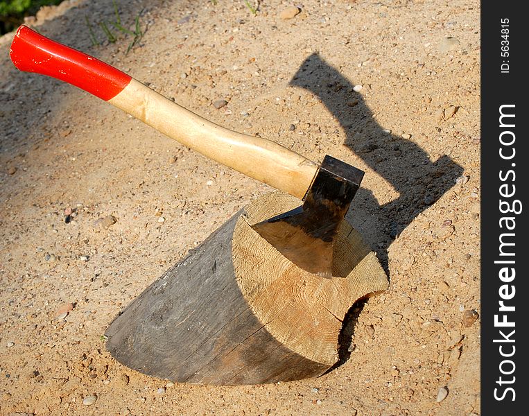 Axe in a tree on background of sand