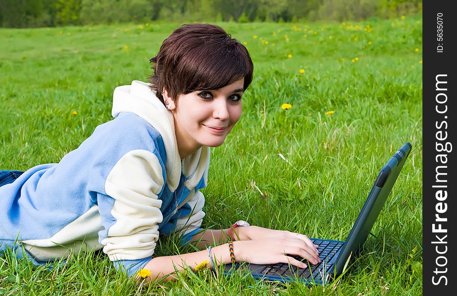 Girl sits on a green grass with a portable computer. Girl sits on a green grass with a portable computer