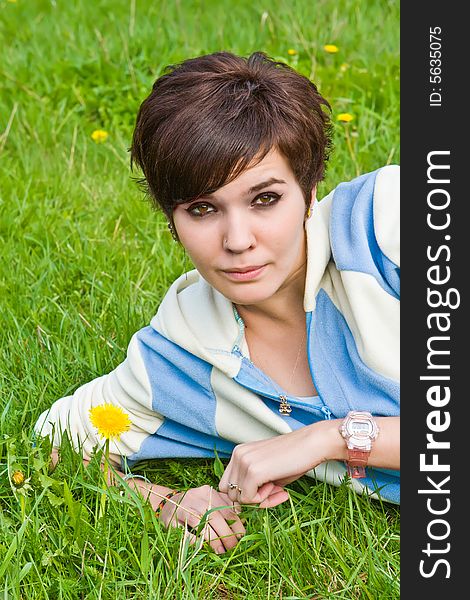 Girl lays on a green grass with yellow dandelions. Girl lays on a green grass with yellow dandelions