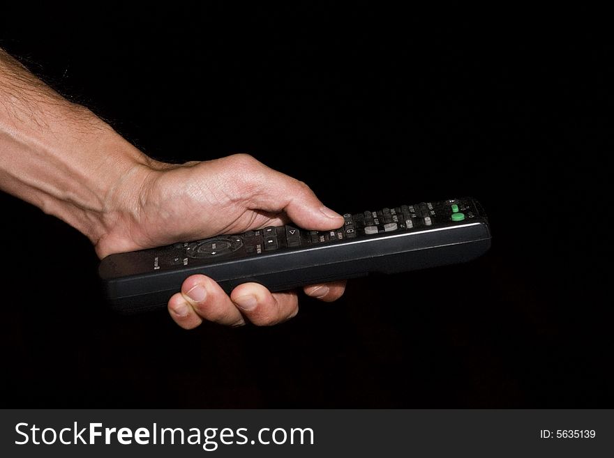 Hand of man holding remote control - low key. Hand of man holding remote control - low key