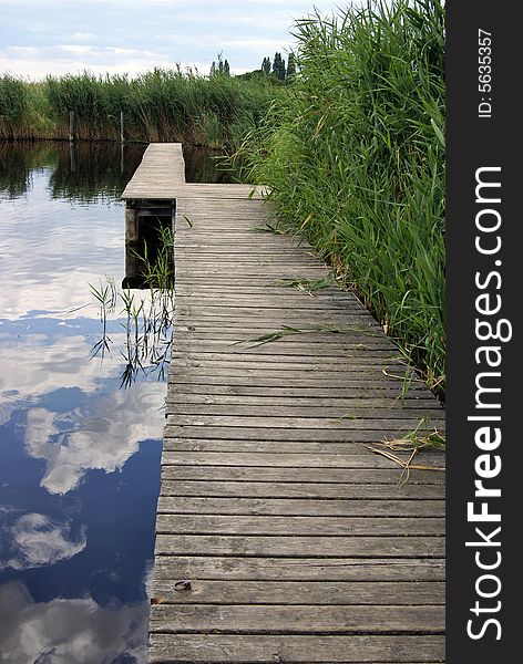 Wooden footbridge in a lake, surrounded by reed. Wooden footbridge in a lake, surrounded by reed