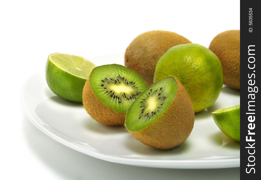 A group of fresh kiwis and limes on a white plate and isolated on white background. A group of fresh kiwis and limes on a white plate and isolated on white background