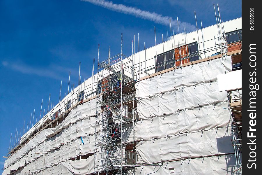 A general view of the exterior of a new modern building site development covered in scaffolding and cladding.