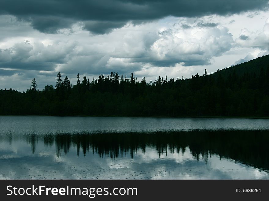 Silhouette of trees behind a silent lake. Silhouette of trees behind a silent lake