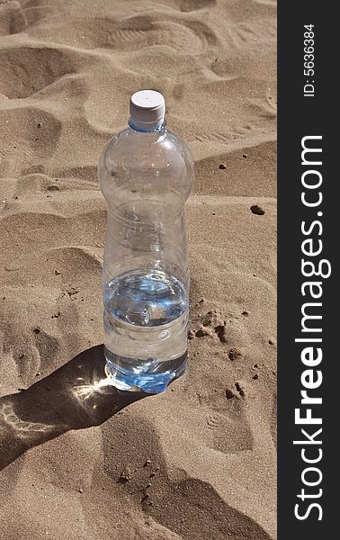Plastic bottle with water on sand.