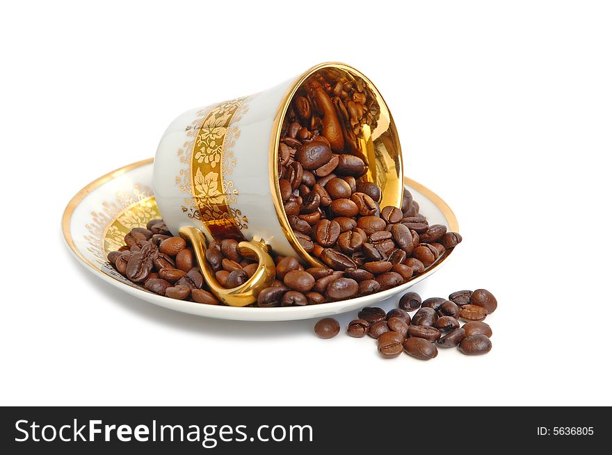 Overturn gold coffee cup with coffee beans