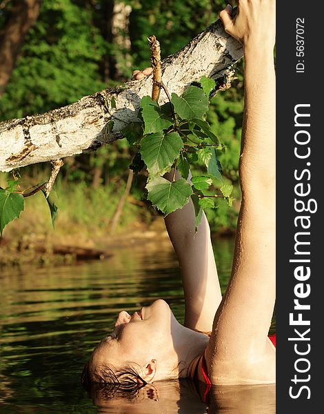 Woman under Tree in Water. Greens and Beach on Background.