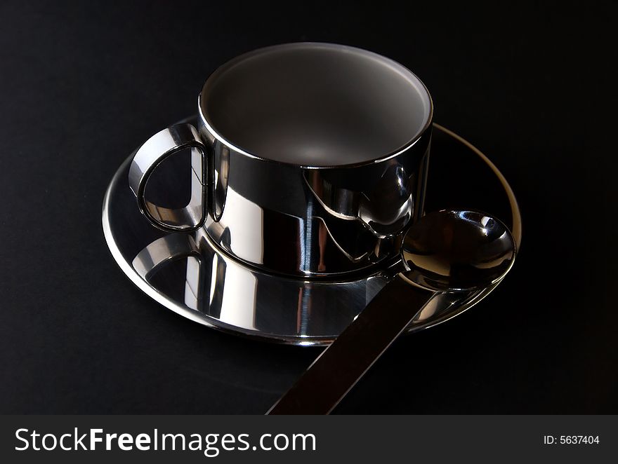 Cup, saucer and teaspoon on the black background. Cup, saucer and teaspoon on the black background