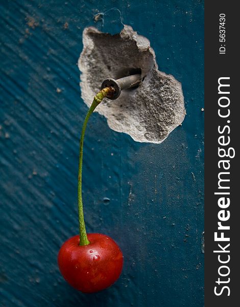 Cherry and screw on a background a wall