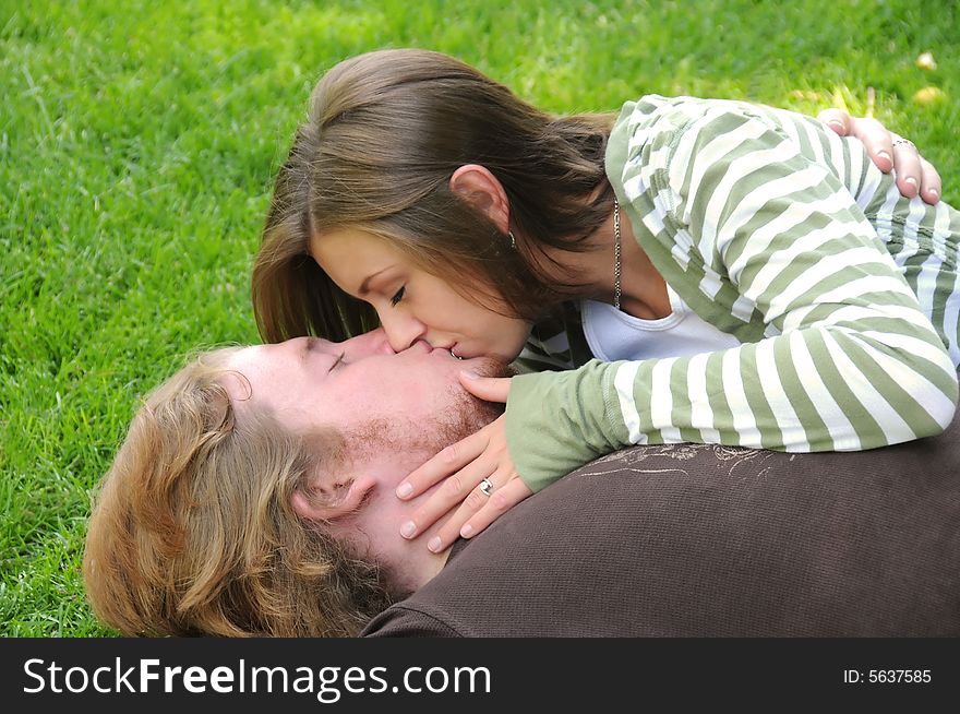 Woman kissing her husband in the grass. Woman kissing her husband in the grass