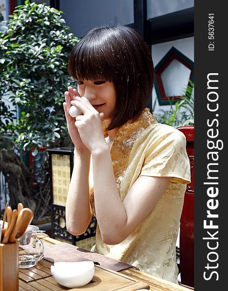 A beautiful Chinese girl is performing tea art in an ancient garden. Chinese characters on the lantern by the tree are the ancient poesy of China. A beautiful Chinese girl is performing tea art in an ancient garden. Chinese characters on the lantern by the tree are the ancient poesy of China.