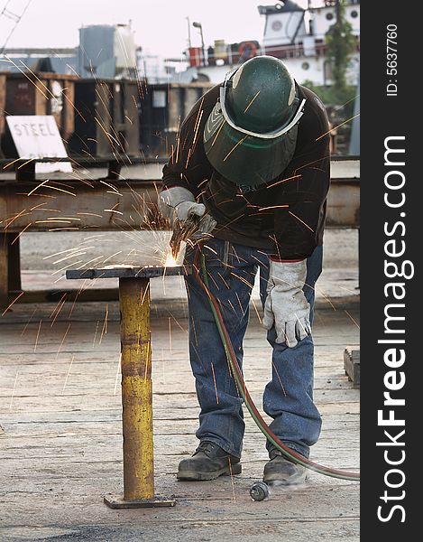 A welder working a torch at shipyard. A welder working a torch at shipyard
