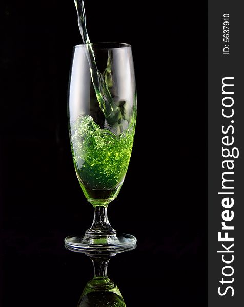 Glass of drink poured on black background