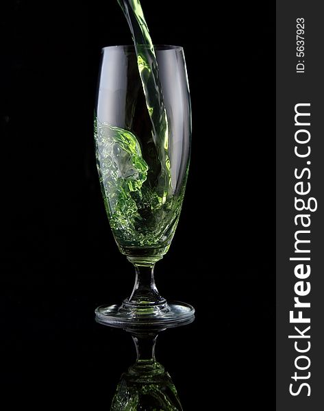 Glass of drink poured on black background