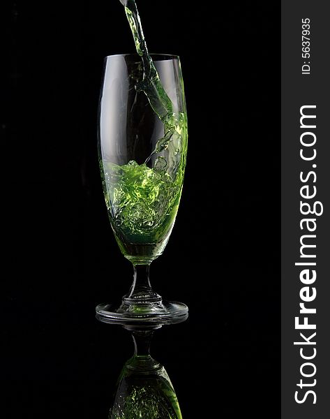 Glass of drink poured on black background